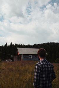 Rear view of man standing on field against sky