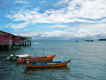 Boats moored on sea by buildings against sky