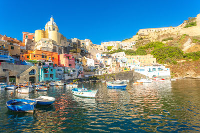 Boats in sea against clear blue sky