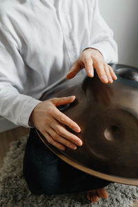 Man playing on hang drum, or steel drum, hangpan, modern steel music instrument at home. meditation