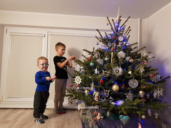 Full length of boy with christmas tree at home