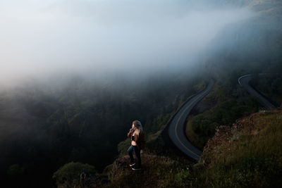 Woman standing on mountain in foggy weather