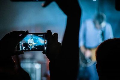 Reflection of people on mobile phone at music concert