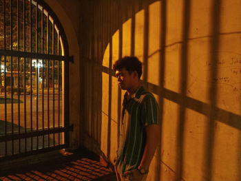 Side view of young man looking through window