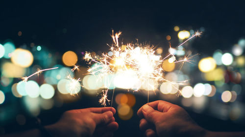 Cropped hands holding sparklers