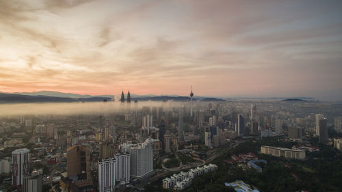 Aerial view of cityscape against cloudy sky at sunset