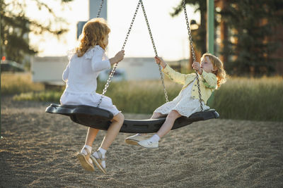 Happy girls swinging on swing at park