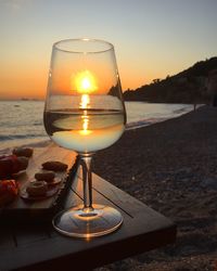Close-up of wine glass on beach