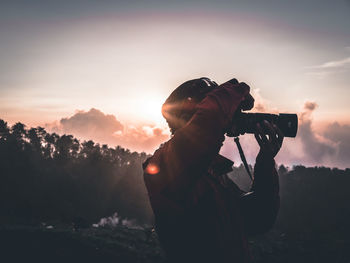 Silhouette person photographing at sunset