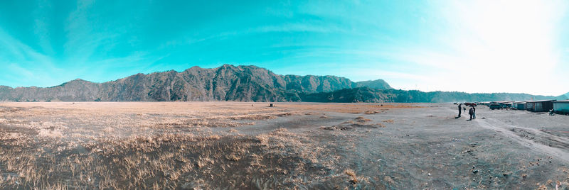 People walking on arid landscape against sky
