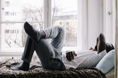 Full length side view of exhausted man sleeping on bed at home