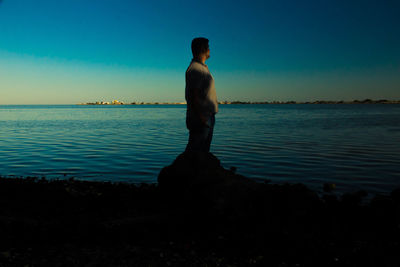 Rear view of shirtless man looking at sea against sky