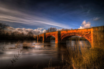 Arch bridge over river against sky