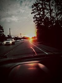 Cars on road against sky during sunset