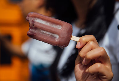 Midsection of woman holding popsicle while standing outdoors