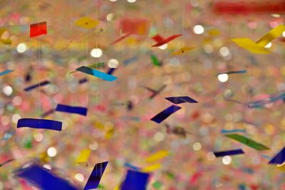 Close-up of multi colored confetti hanging against abstract backgrounds