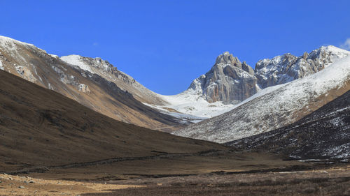 Scenic view of snowcapped mountains against blue sky