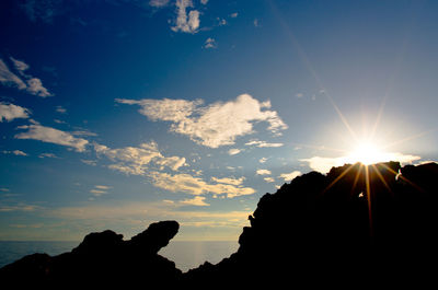 Silhouette rocks against sky during sunset