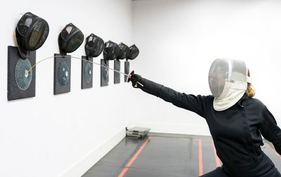 Woman hitting target with fencing sword at gym