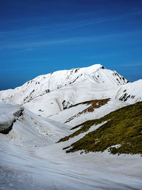 Scenic view of snowcapped mountain against blue sky