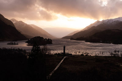 Scenic view of lake and mountains against sky during sunset