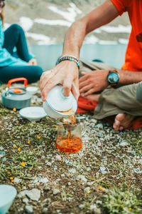 Low section of man pouring tea while sitting at beach