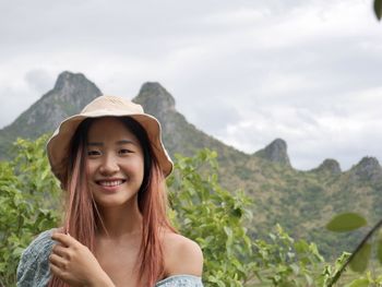 Portrait of young woman standing against mountain