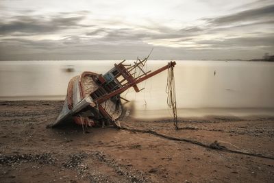 Traditional windmill on beach against sky during sunset