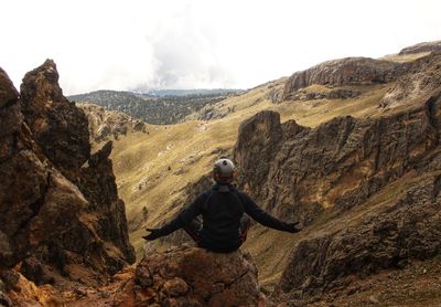 Rear view of man on rock against sky