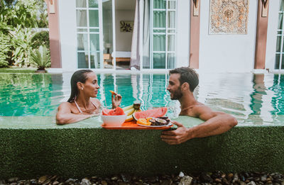 Friends sitting by swimming pool