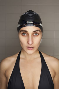 Portrait of beautiful young swimmer woman with black swimwear hat and swimming goggles