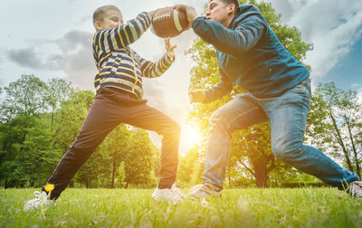 Father and son playing football. man teaching boy rugby outdoors in sunny day. family sports weekend