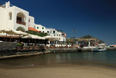 Buildings by sea against clear sky