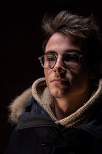 Close-up of thoughtful young man looking away against black background