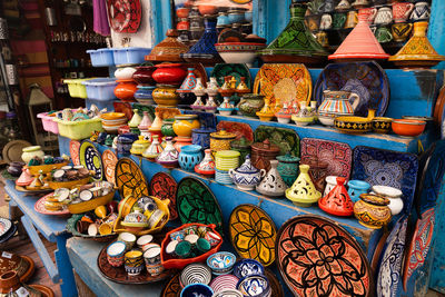 Colourful moroccan style plates, bowls, cups and tajine pots on shelf for sale, essaouira, morocco.