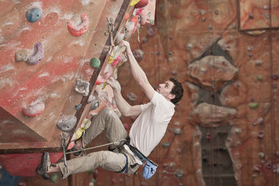 Young man practising at indoor climbing wall in the uk
