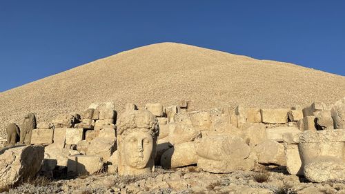 Low angle view of rock formations against clear blue sky