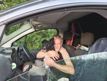 Portrait of man with dog sitting in car
