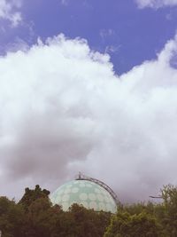 Low angle view of trees against cloudy sky
