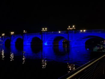 Illuminated bridge in city against sky at night