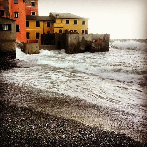 building exterior, architecture, built structure, water, sea, wave, beach, sky, shore, surf, building, waterfront, residential building, residential structure, city, outdoors, house, day, motion, no people