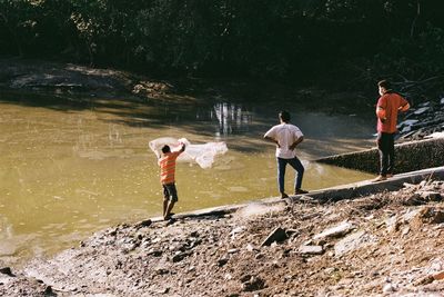 Rear view of people standing on rocks at shore