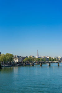 View of buildings by river against blue sky