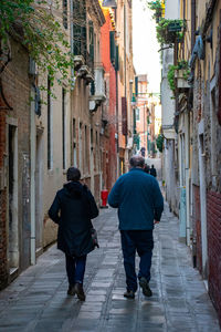 Full length rear view of people walking on street amidst buildings