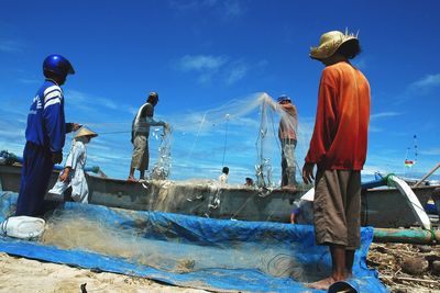 Fishermen with net at beach against sky