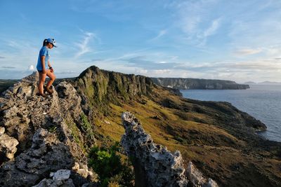 Man on rock by sea against sky