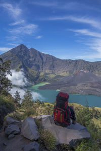 A man behind a huge backpack looking at mount rinjani, lombok, indonesia.