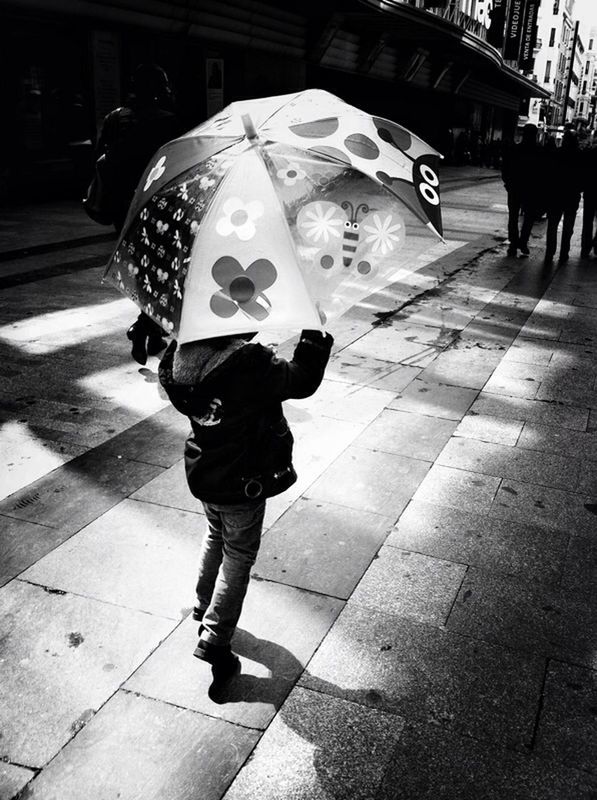 full length, street, lifestyles, casual clothing, walking, city life, city, leisure activity, sidewalk, shadow, sunlight, front view, standing, building exterior, childhood, outdoors, incidental people, city street