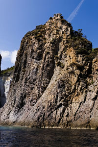 Rock formation by sea against clear sky