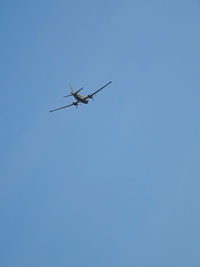 Low angle view of airplane against clear blue sky